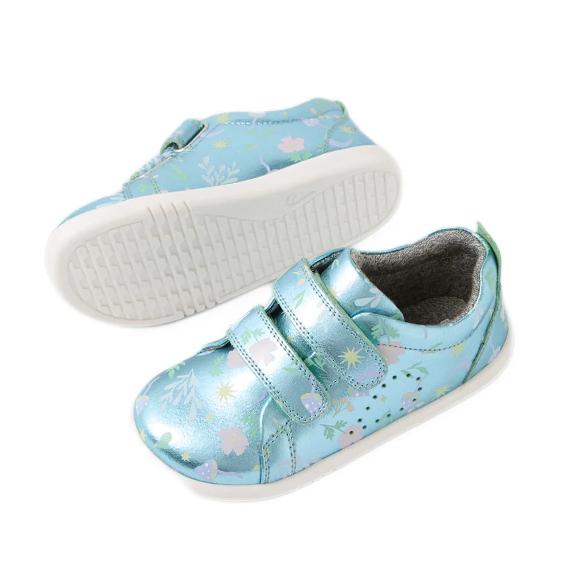 Bobux Iwalk Toddlers Grass Court Jelly Mint Metallic Leather Trainers in blue feature a shiny metallic finish, playful floral patterns, white rubber soles, and two velcro straps. One trainer is positioned upright to showcase the top design, while the othe