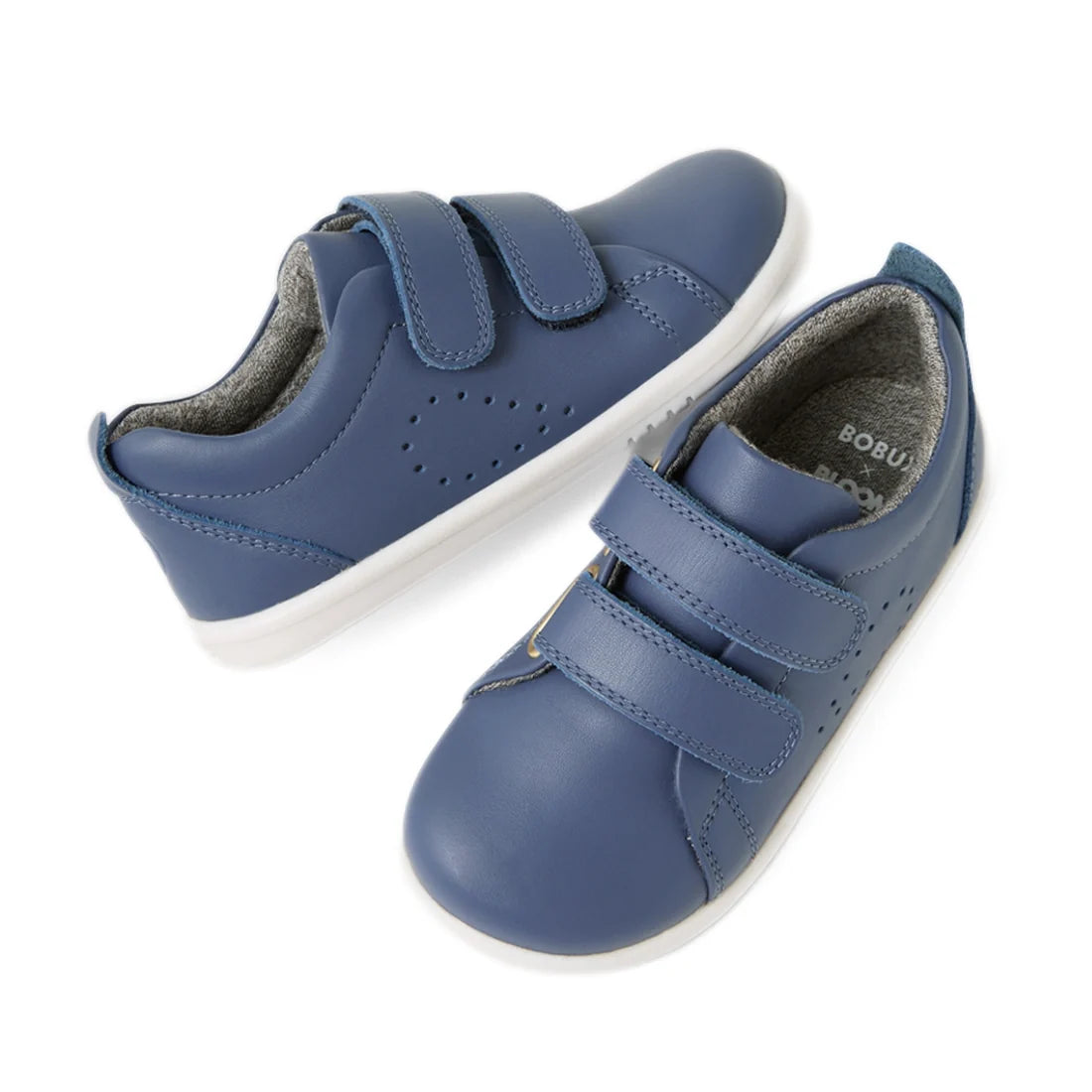 A pair of Bobux Iwalk Toddlers Grass Court Vintage Indigo Blue Leather Trainers with white soles and velcro straps, displayed on a white background.