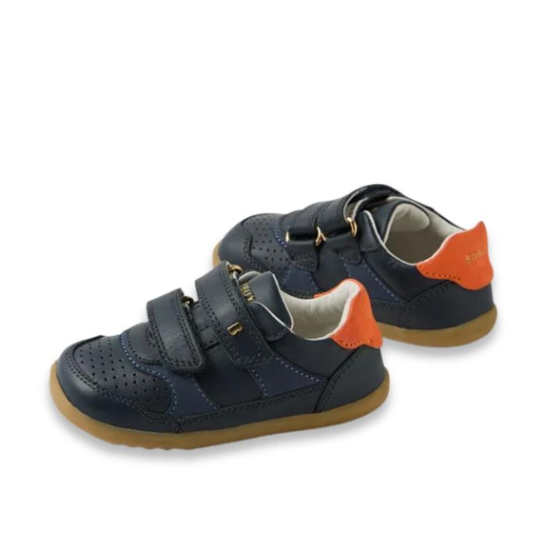 The Bobux IW Iwalk Hunter Leather Sneaker Navy is a pair of navy kids' leather sneakers featuring perforated details, tan rubber soles, orange heel accents, and two adjustable straps. Displayed on a white background., 9420074834096, 9420074834102, 9420074