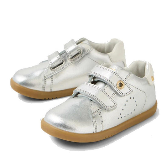 The Bobux IW Iwalk Maverick Leather Sneaker Silver features shiny silver leather, light brown soles, double velcro straps, side perforations for breathability, and metallic details—perfect for kids.