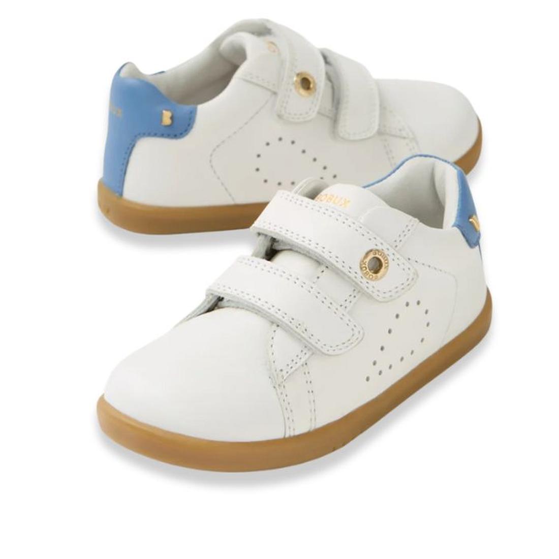 The Bobux IW Iwalk Maverick Leather Sneaker in White Coronet Blue features breathable leather, light brown soles, blue heel accents, gold eyelets, and two adjustable straps. Shown on a white background.