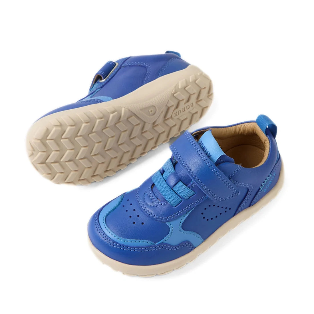 Two Bobux IW Iwalk Neo Toddlers Leather Sneakers in Dazzling Blue are shown: one upright and one on its side to display the textured, white zero drop sole designed for natural foot movement. These barefoot-inspired sneakers feature velcro straps, light bl