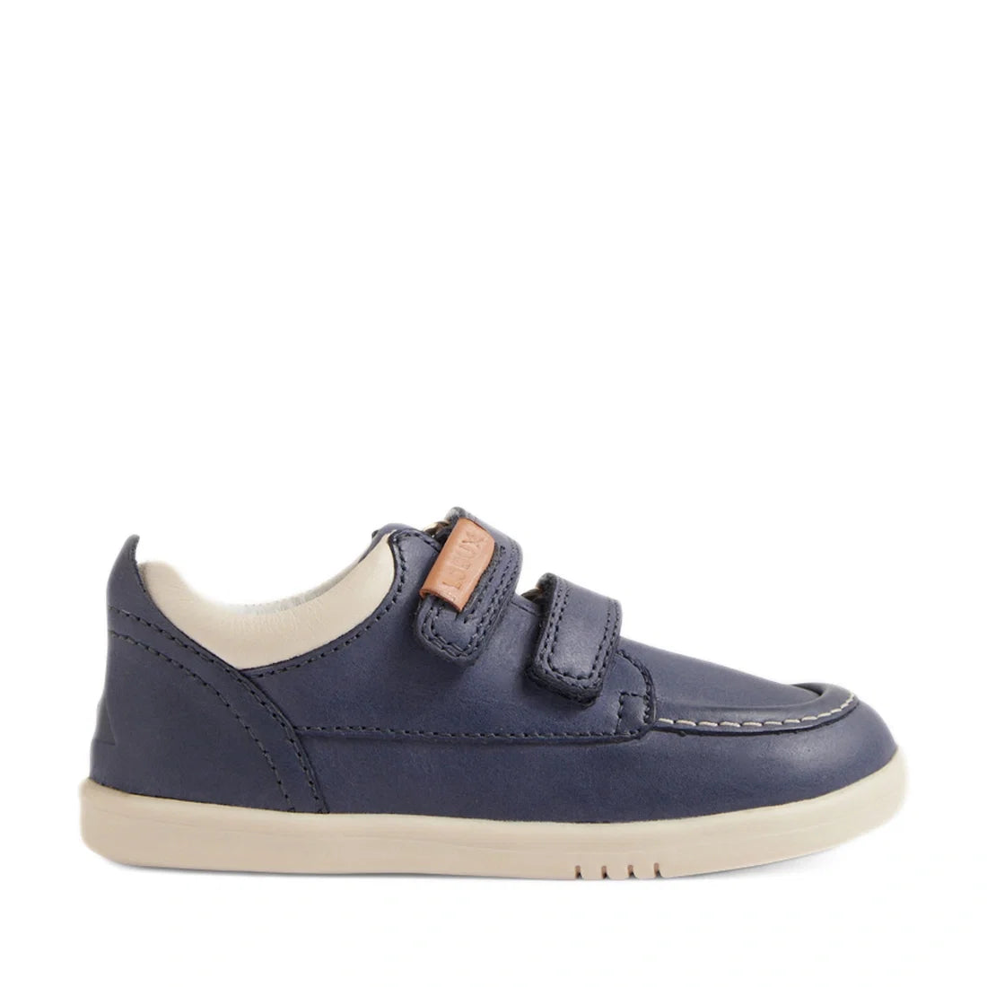 The Bobux IW Iwalk Oakley Toddlers Leather Sneaker in Vintage Blue features a navy blue leather upper, two hook-and-loop straps, white lining, a lightweight beige sole, and visible stitching on the toe area reminiscent of a moccasin boat shoe, shown in si