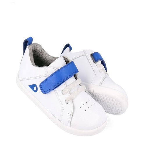 The Bobux Kids IWalk IW Pace Sneaker White Blue 650401 features white leather, gray soles and elastic laces, blue unisex velcro straps, and blue accents on the side and heel tab, shown against a plain white background.