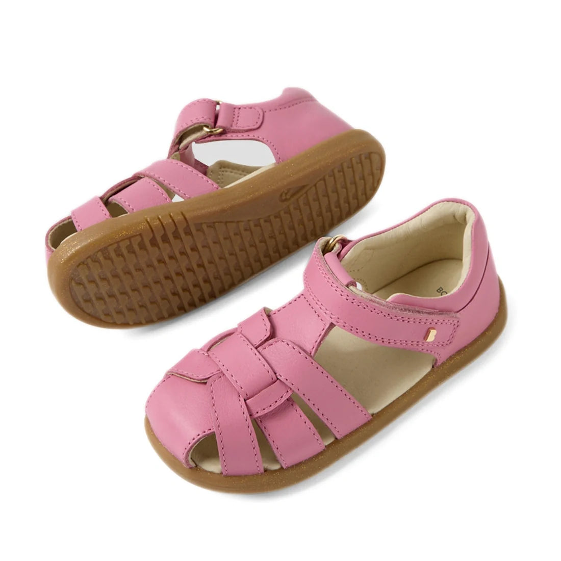 A pair of Bobux IWalk Skip Twist Sandal Cashmere Rose Pink Closed Toe Toddlers, featuring pink leather uppers, brown rubber soles, and a Velcro strap, displayed on a white background., 9420074854018, 9420074854025, 9420074854032, 9420074854049, 9420074854