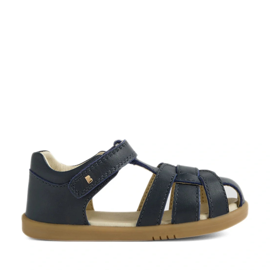 The Bobux IWalk Skip Twist Sandal Navy Closed Toe Toddlers is a navy blue sandal for children featuring a tan rubber sole and an open toe, with a secure Velcro strap at the ankle. Designed as breathable kids’ shoes, this sandal includes multiple straps ac