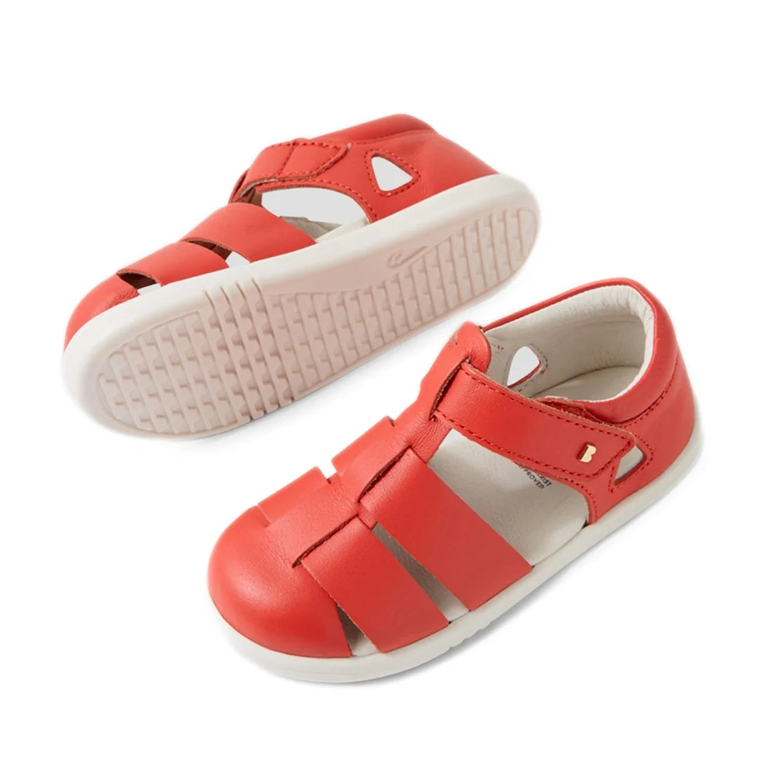 A pair of Bobux IWalk Tidal Sandal Grenadine Red Closed Toe Toddlers is displayed from a side and bottom view against a white background, featuring closed toes, white soles, and velcro straps. These leather sandals are designed to be both stylish and wate