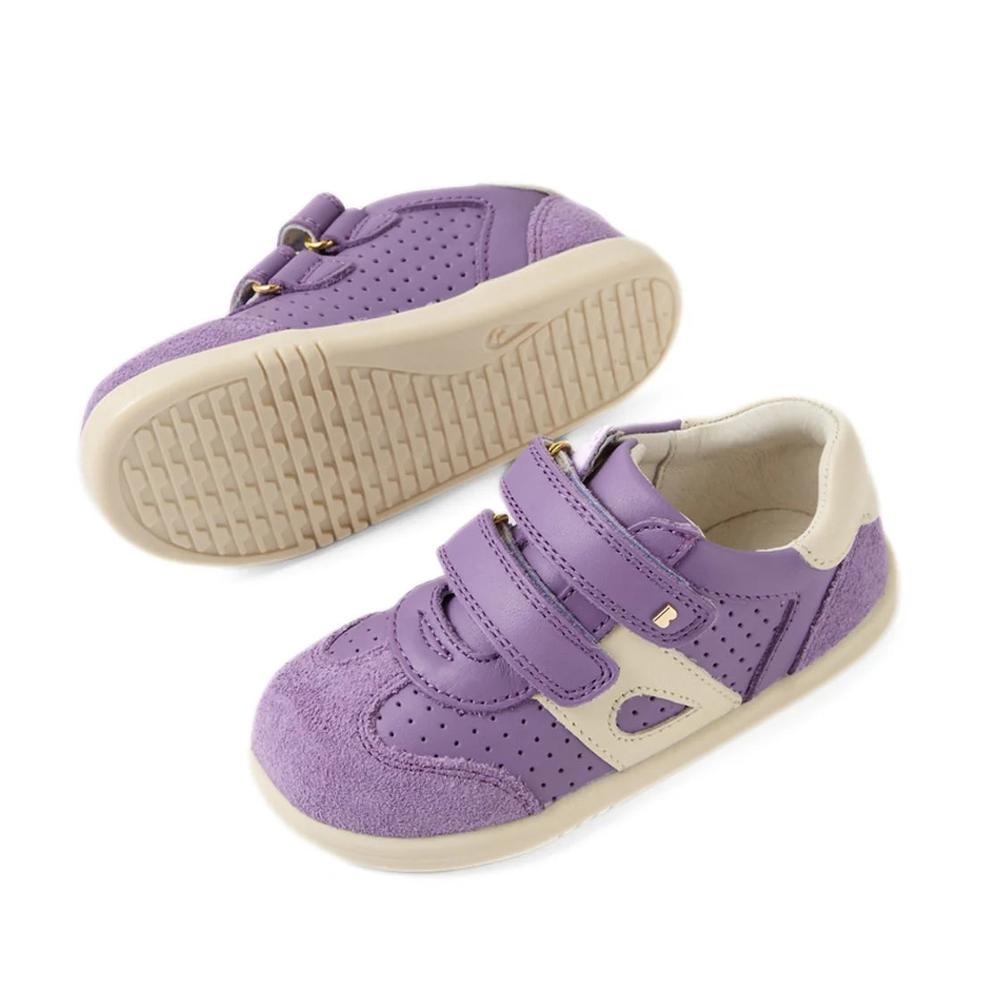 A pair of Bobux IW Iwalk Toddlers Titan Purple Haze Leather Trainers with beige accents, featuring Velcro adjustable straps and rubber slip-resistant soles; one shoe is lying on its side while the other stands upright, displaying the tread pattern., 94200