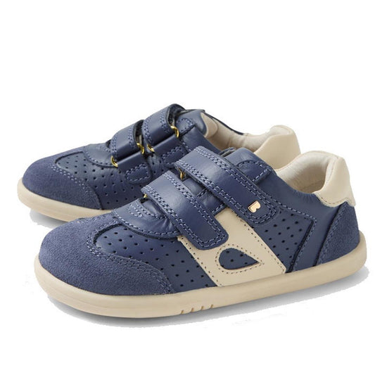 The Bobux IW Iwalk Titan Leather Sneaker in White and Vintage Indigo Blue features perforated detailing, beige accents, and two velcro straps for kids, shown on a white background.