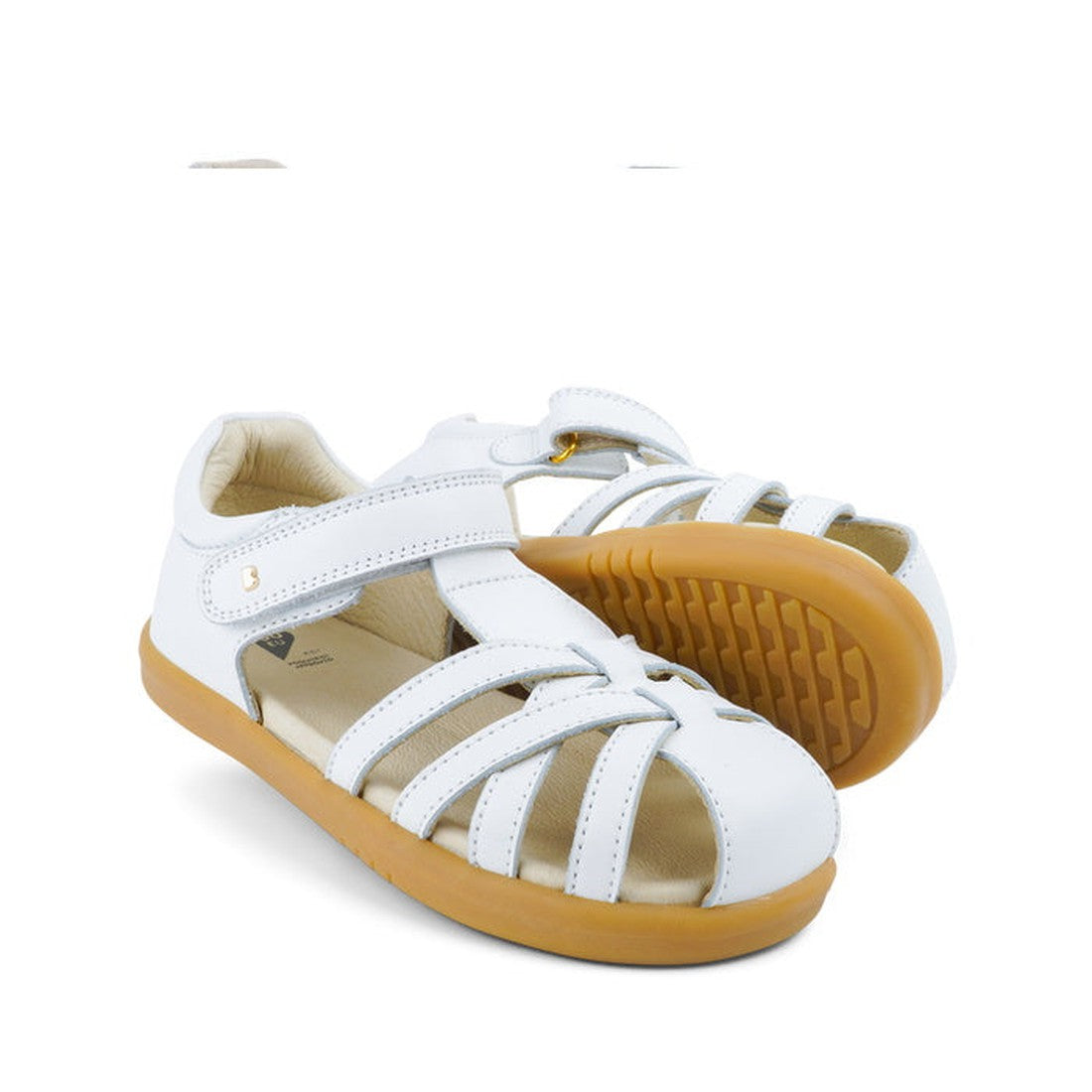 The Bobux Kids + Plus Girls Cross Jump White Leather Sandal 837006 features closed toes, Velcro straps, and tan rubber soles, shown on a white background.