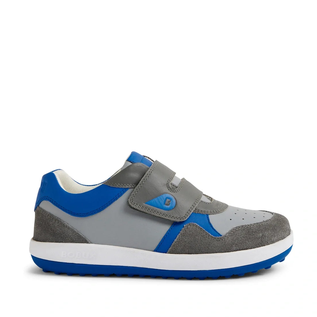 The Bobux KP Kids Plus Baseline Leather Sneaker Ultimate Grey is a children’s sneaker featuring grey and blue panels, hook-and-loop Velcro straps with a small B logo, a white cushioned EVA midsole, and a blue rubber sole. Crafted from suede and synthetic 