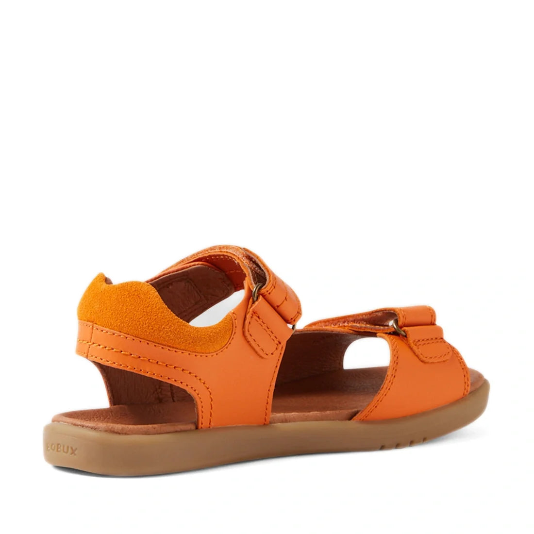 The Bobux KP Kids Plus Driftwood Leather Sandal in Orange Peel is a boys’ leather sandal with an open toe, flat brown sole, Velcro straps, and a closed heel. Designed as practical kids’ walking shoes, it is seen from the back right angle against a white b
