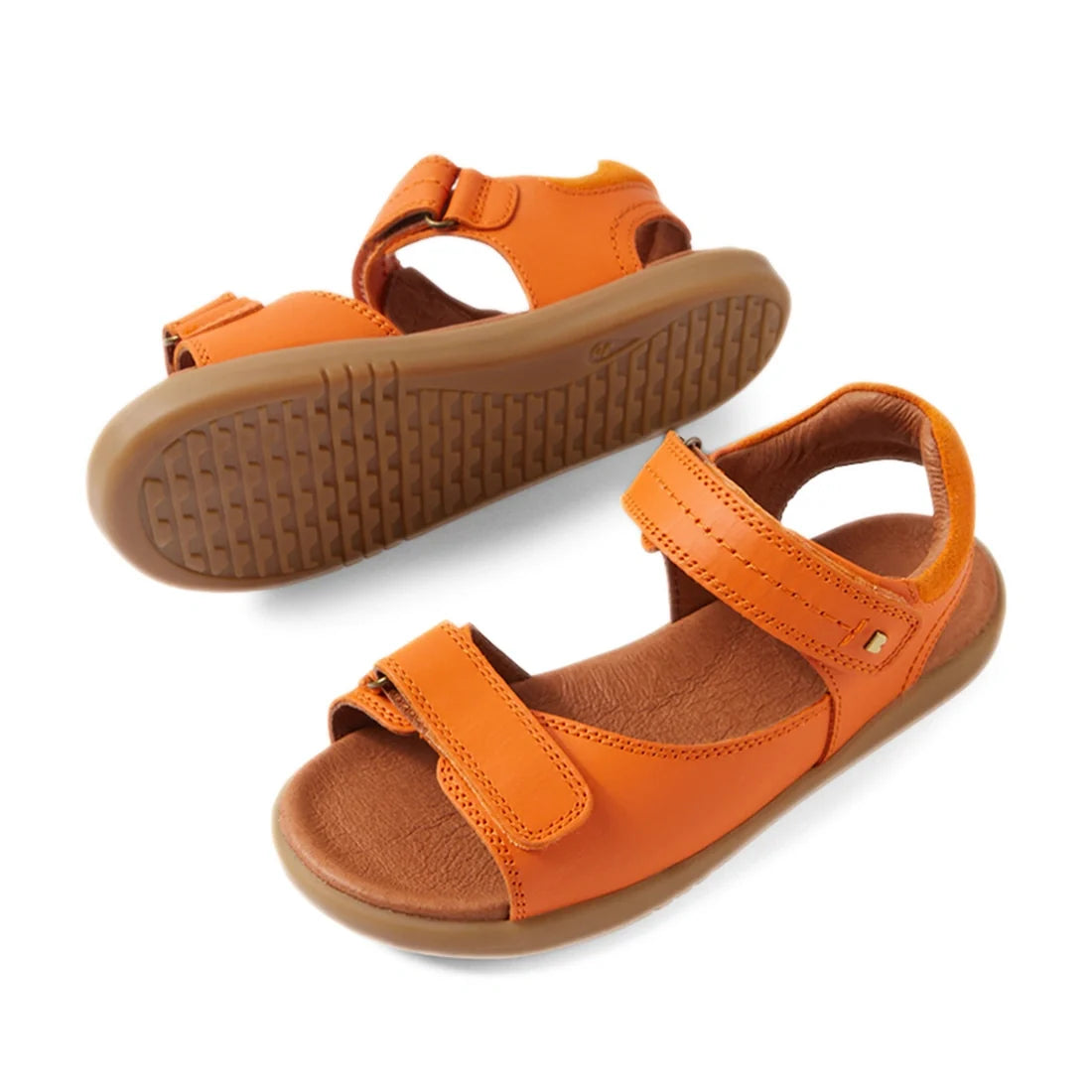 A pair of Bobux KP Kids Plus Driftwood Leather Sandal Orange Peel, featuring orange leather with brown soles and adjustable straps over the toes and around the ankle, displayed against a white background., 9420074859020, 9420074859037, 9420074859044, 9420