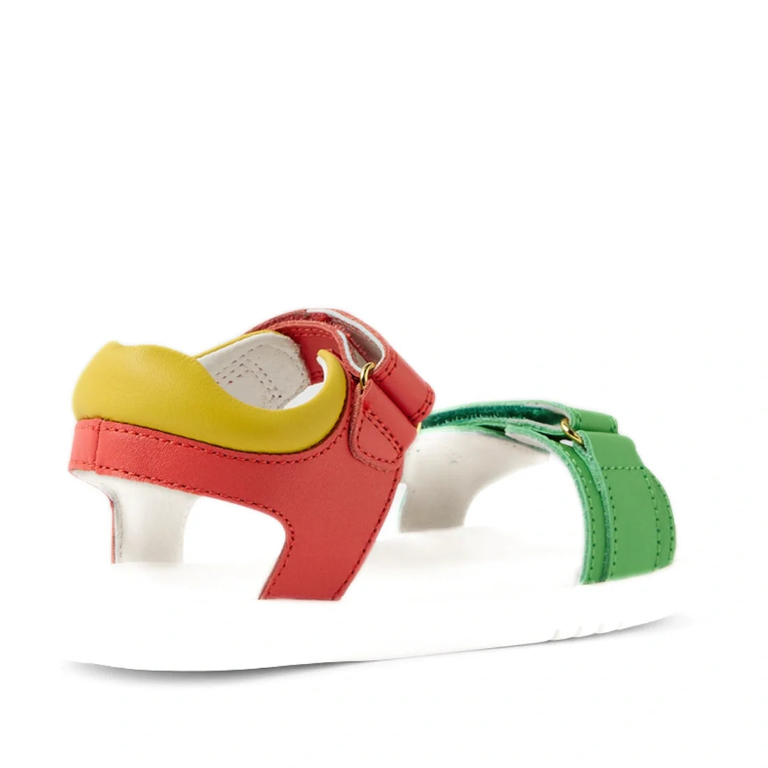 The Bobux KP Kids Plus Dune Leather Sandal Grenadine Red is a colorful kids’ leather sandal with a white sole, featuring red, green, and yellow leather straps with adjustable closures for a secure fit. The sandals are shown from the side and slightly behi