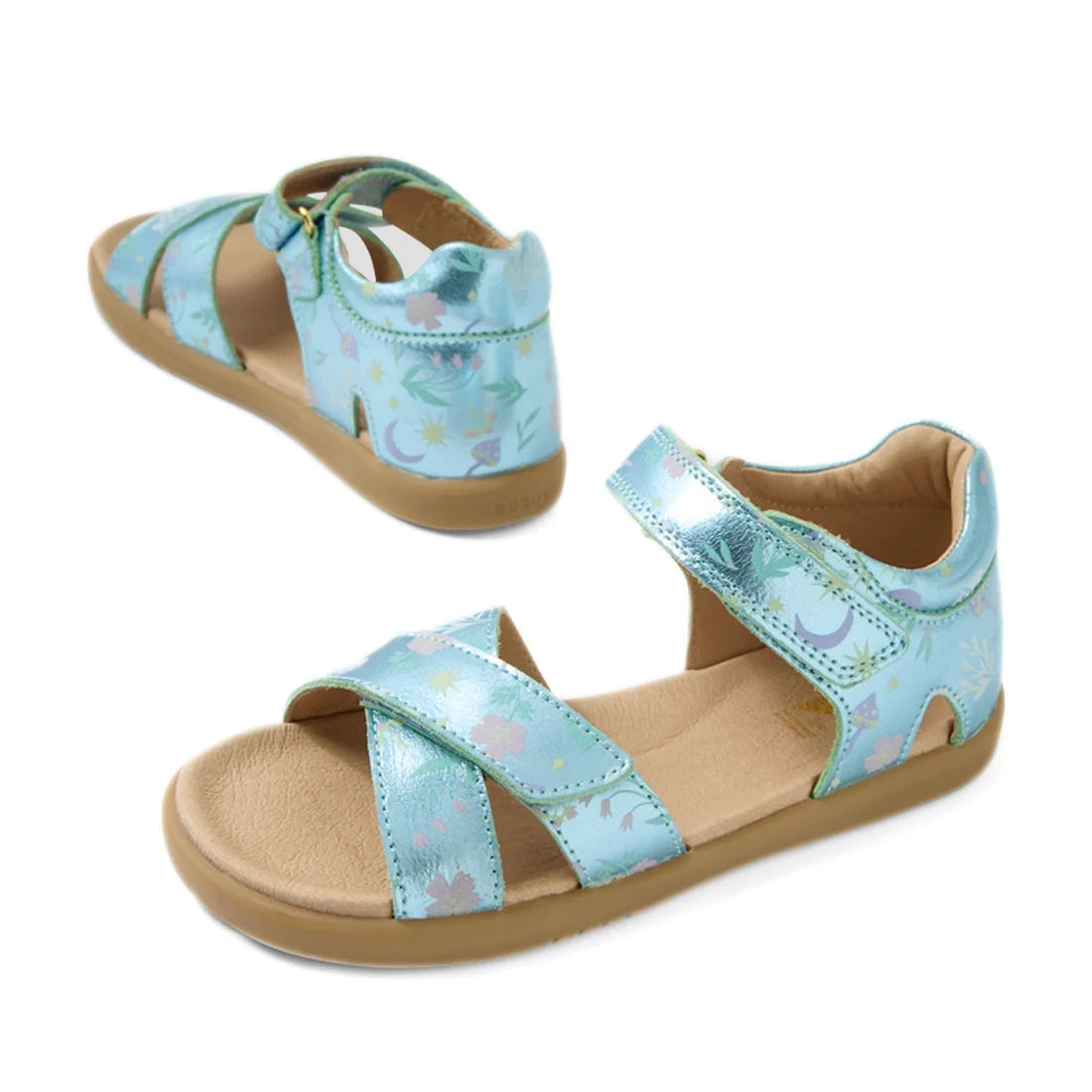 Two Bobux KP Kids Plus Flora Leather Sandal Jelly Mint Metallic Blue, featuring a light blue metallic floral pattern, tan soles, open toes, and ankle straps, are shown from front and back angles against a white background.