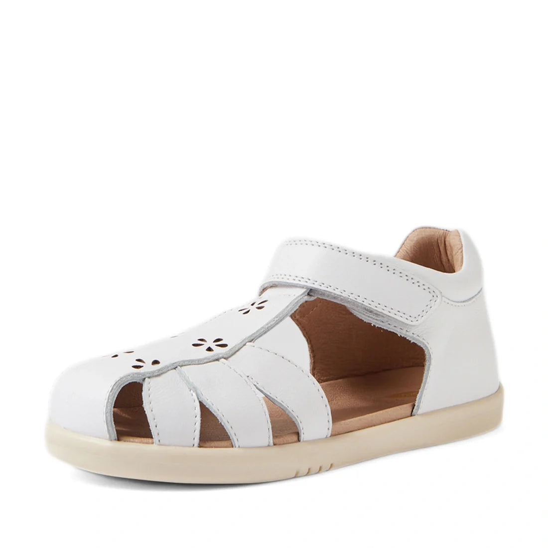 Introducing the Bobux Kid+ Plus KP Holly White Closed Toe Sandal for girls—elegant footwear with a closed toe design, charming floral cut-out patterns, and an easy Velcro strap. Featuring a beige sole and light brown lining, these sandals are crafted in B