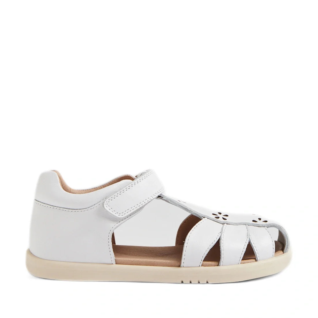 Introducing the Bobux Kid+ Plus KP Holly White Closed Toe Sandal—a white children’s sandal crafted from leather with a closed heel, cut-out sides, velcro strap, delicate floral cutout detailing on the toe, and a beige rubber sole. These stylish sandals ar