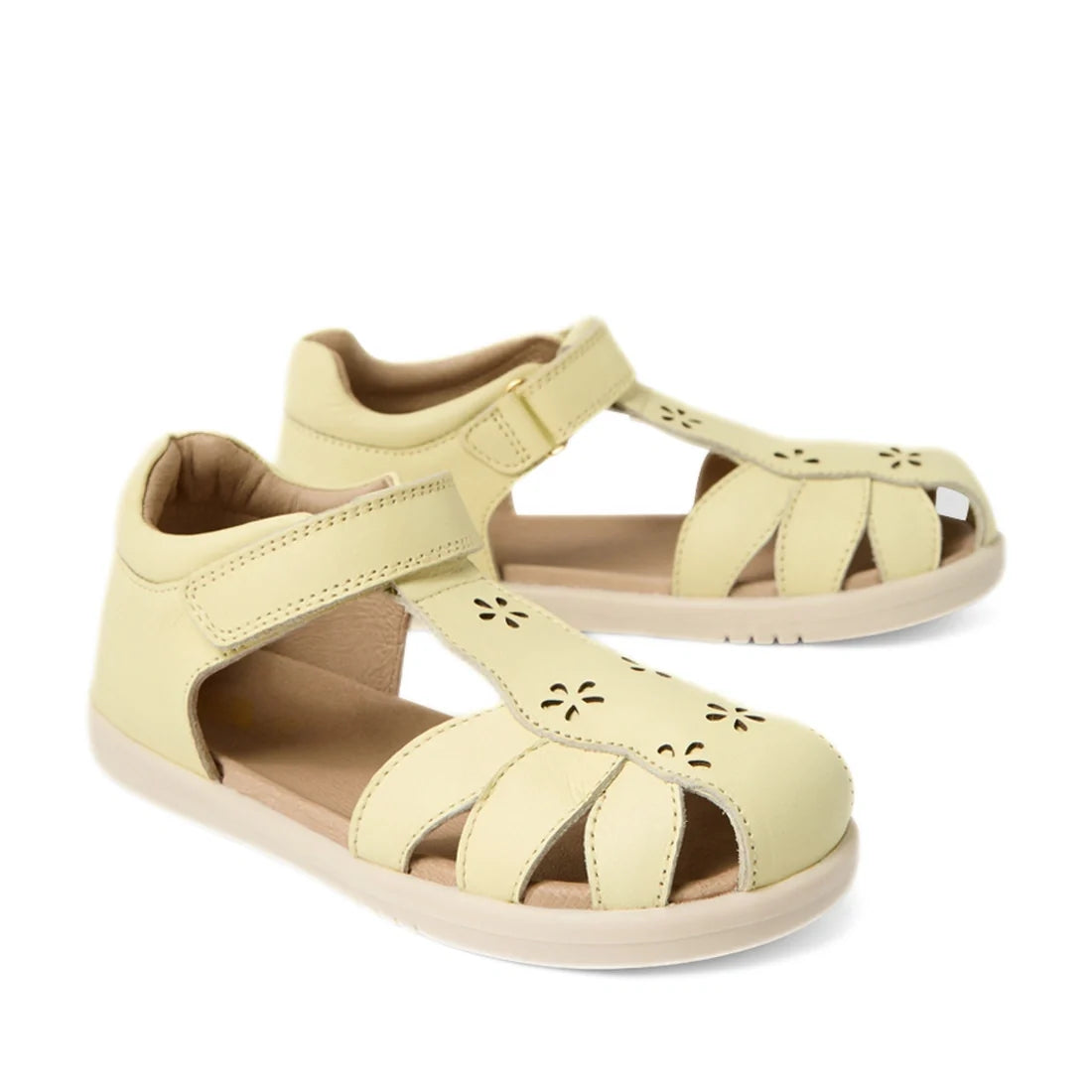 Pair of Bobux Kid+ Plus KP Holly Wax Yellow Closed Toe Sandals for children, featuring charming cut-out flower details and adjustable Velcro straps. These leather sandals are displayed on a white background.