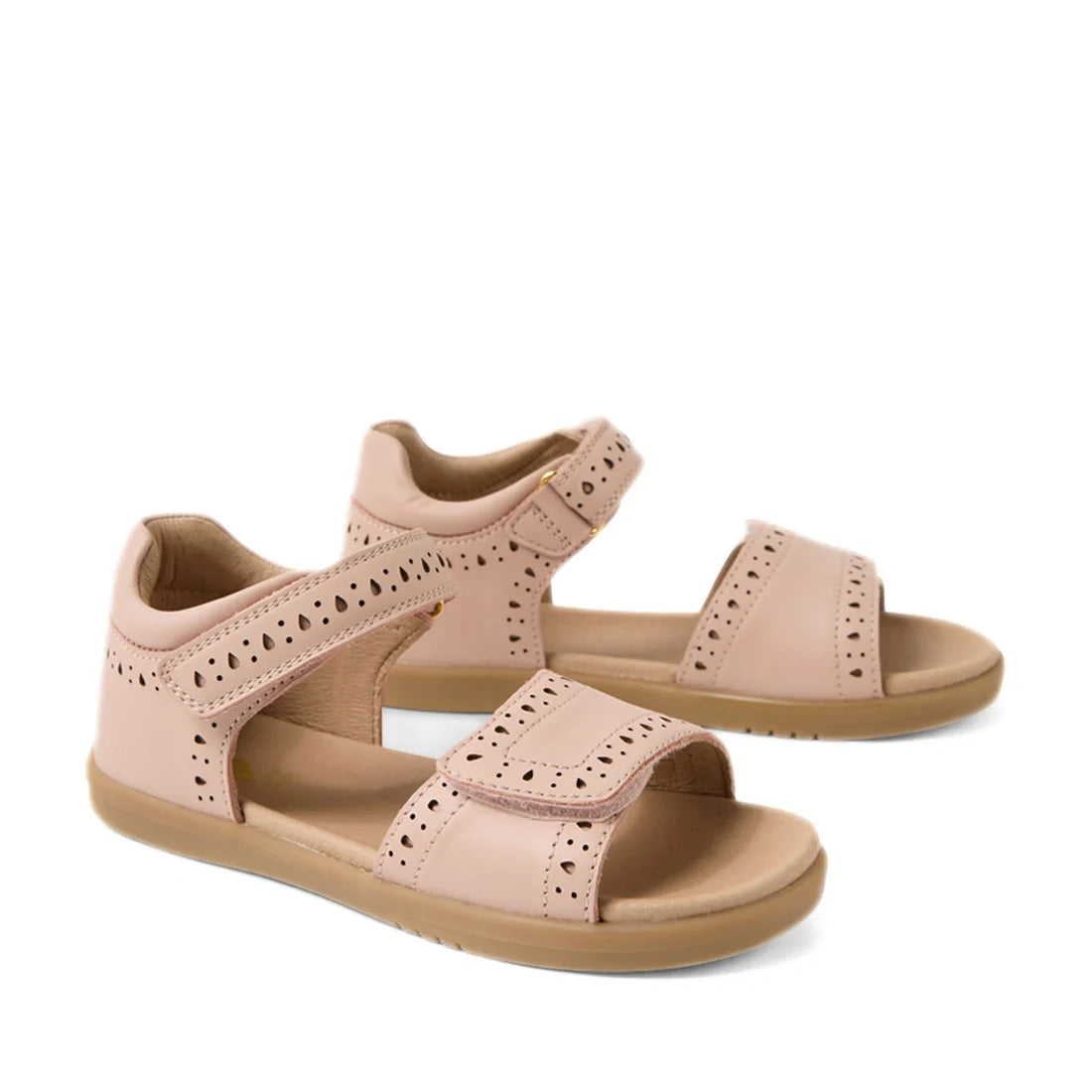 A pair of Bobux Kid+ Plus KP Logan Cameo Rose Pink Open Toe Sandals for girls, featuring light brown soles, stylish cut-out patterns, and adjustable Velcro straps over the toes and around the ankles. These leather sandals provide both comfort and style fo