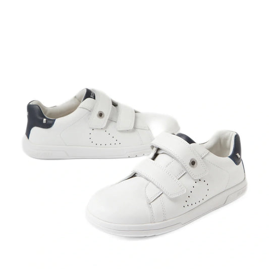 A pair of Bobux Kid+ Plus KP Maverick Leather Sneaker White Navy shoes, featuring white leather with navy accents and adjustable hook-and-loop Velcro straps, displayed on a white background.