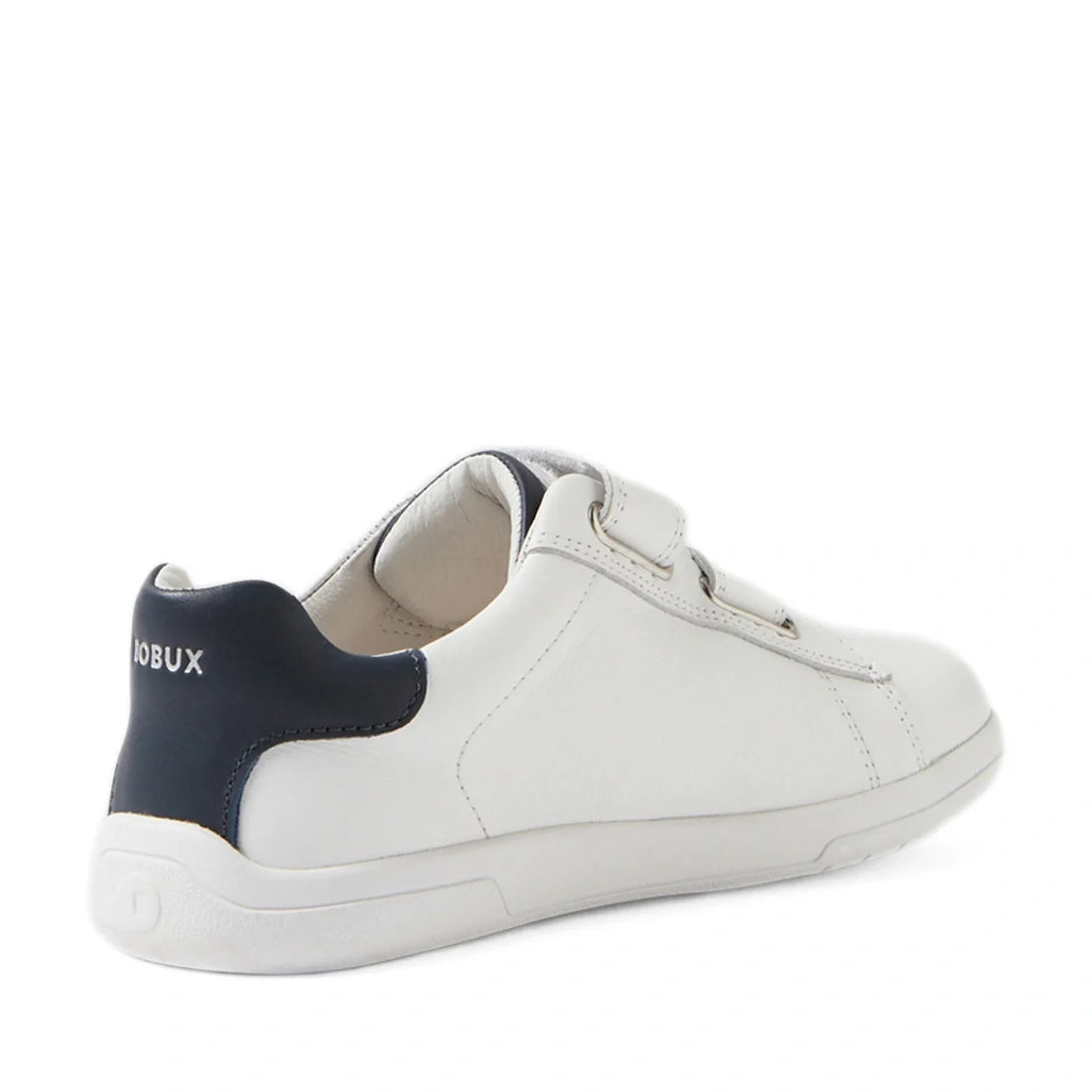 The Bobux Kid+ Plus KP Maverick Leather Sneaker in White Navy is pictured from a rear side angle on a white background, featuring white leather, a navy heel accent, an adjustable Velcro strap, and “BOBUX” branding on the back.