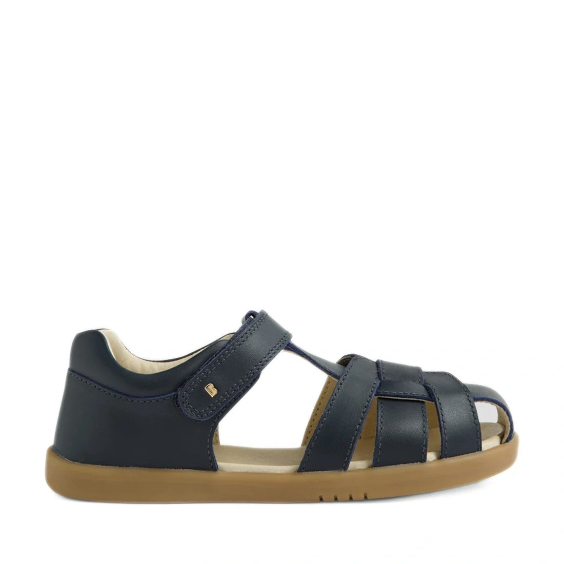 The Bobux Kids Plus KP Skip Twist Navy Closed Toe Sandal features a navy blue design with a tan rubber sole, Velcro strap, and open sides for enhanced breathability. Ideal as summer footwear, these children’s sandals are shown against a plain white backgr