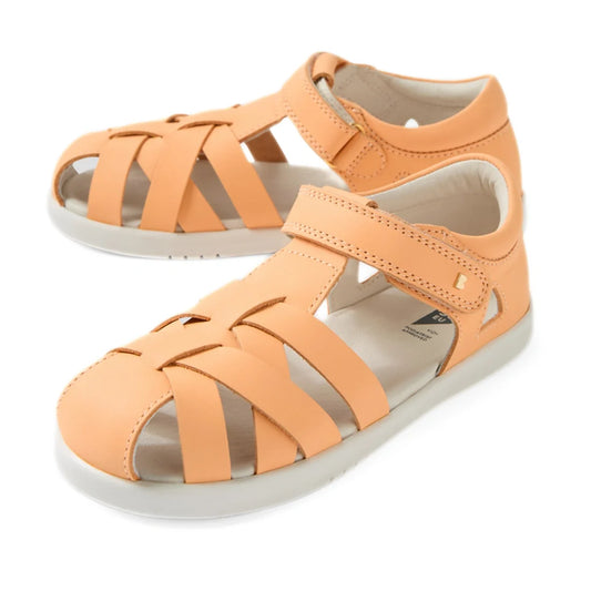 A pair of Bobux Kids Plus KP Tropicana II Peach Jelly Quick Dry Sandals, featuring a peach color, closed-toe leather design with velcro straps and white soles, displayed on a white background. These podiatrist-approved kids’ shoes combine comfort and styl