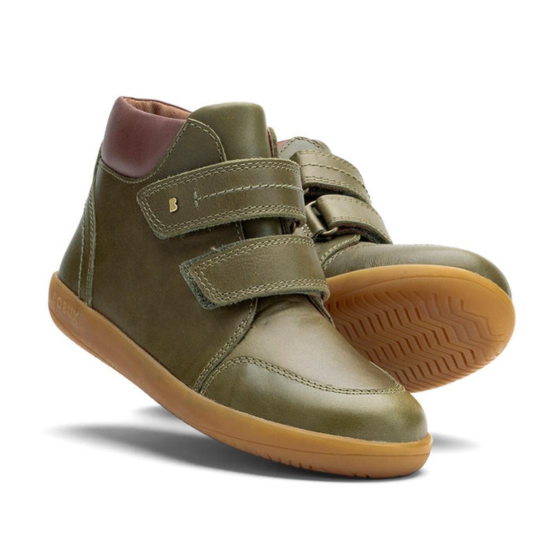 The Bobux Kid+ Timber Boot Olive 832909F features olive green high-top design, tan rubber soles, and two Velcro straps, combining sporty style with the practicality of unisex boots.