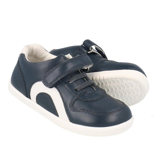 The Bobux Kids IWalk IW Comet Sneaker Navy/White is a retro unisex pair with white soles, side accents, laces, and a velcro strap for easy fastening, shown against a white background.