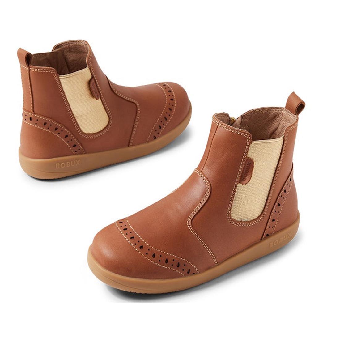 The Bobux Kid+ KP Billie 2 II Girls Leather Boot in Caramel Tan for juniors features tan elastic side panels, decorative perforations, a convenient zipper closure, and flexible rubber soles—shown from a side and angled view.