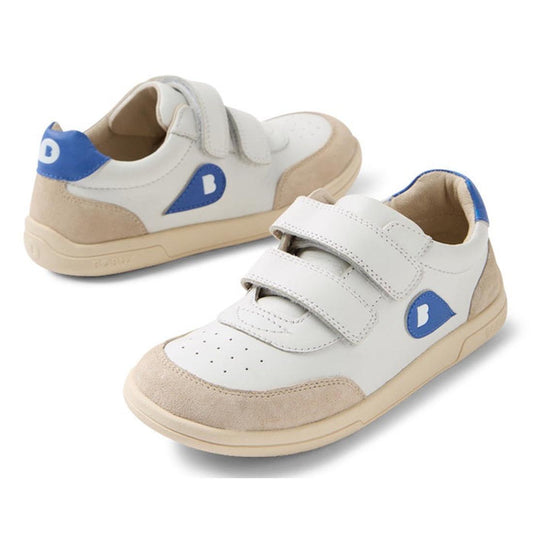 The Bobux KP Kids Plus Champ II Sneaker White Blue Juniors is a white and beige kids' leather sneaker with blue accents, two Velcro straps, a durable sole, and a blue patch with a white "B" on the side.