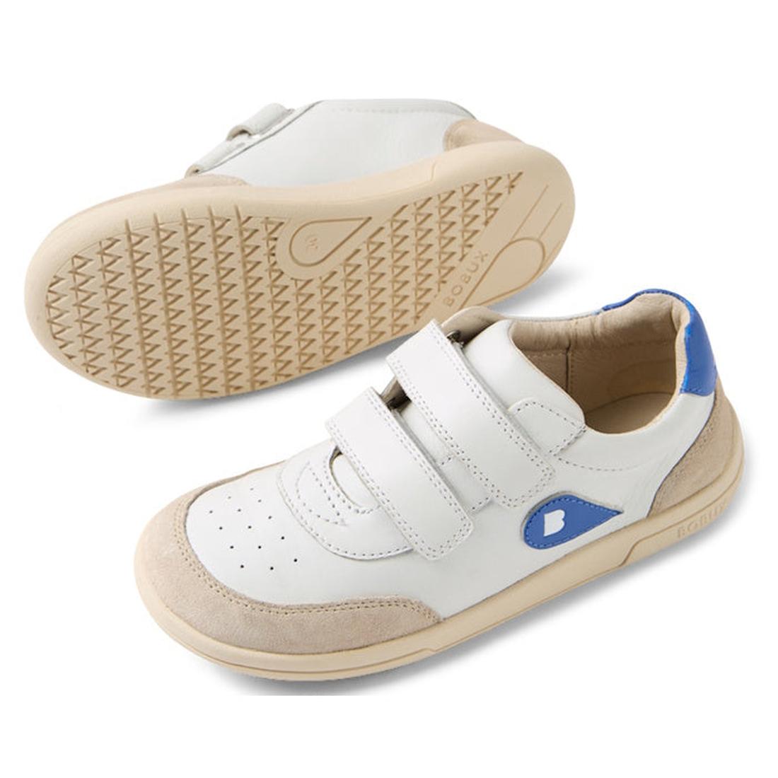 The Bobux KP Kids Plus Champ II Sneaker White Blue Juniors features white leather, beige soles and toe caps, blue accents on heel and side, and two Velcro straps. One shoe is upright; the other is on its side showing the durable sole., 9420074829924, 9420