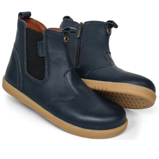 The Bobux Kid+ Jodphur Leather Boot Navy Blue 830007Z is a unisex kids' boot with side zippers, elastic panels, and light brown rubber soles. Stylishly showcased against a white background.