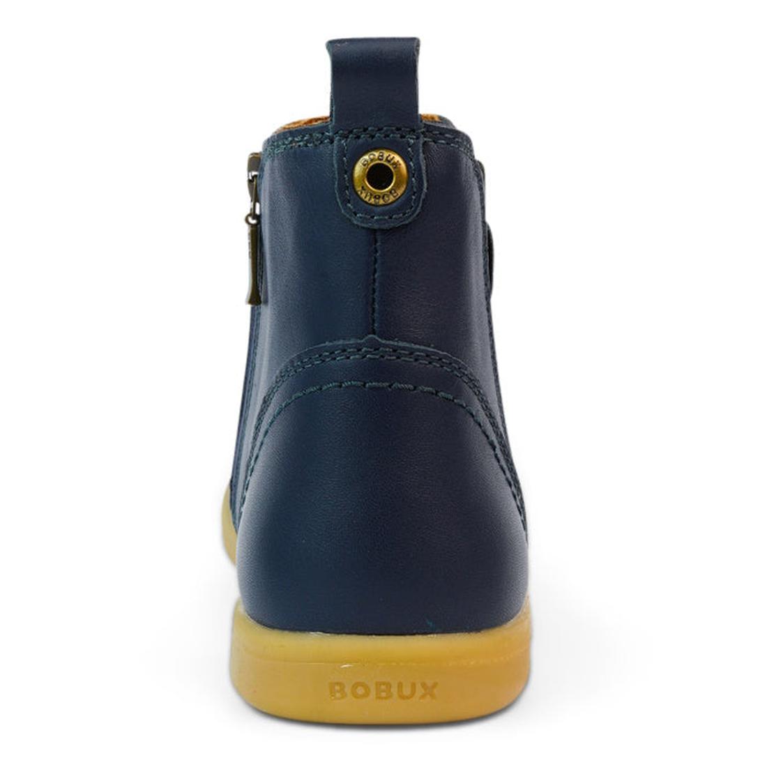 A rear view of the Bobux Kid+ Jodphur Leather Boot Navy Blue 830007Z shows its navy leather, tan rubber sole, gold eyelet, side zipper, and BOBUX embossed on the back of the sole., 9420075720930, 9420075720947, 9420075720954, 9420075720961, 9420075720978,