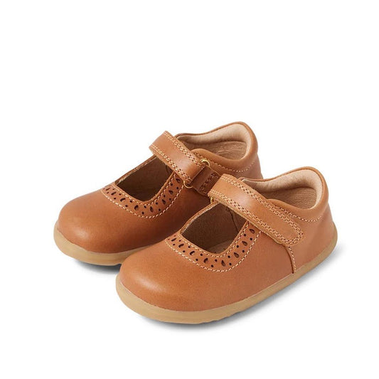 The Bobux Step Up Mary Jane Lola Caramel Tan 752801 are kids’ brown leather shoes with rubber soles, decorative perforations, and adjustable Velcro straps.