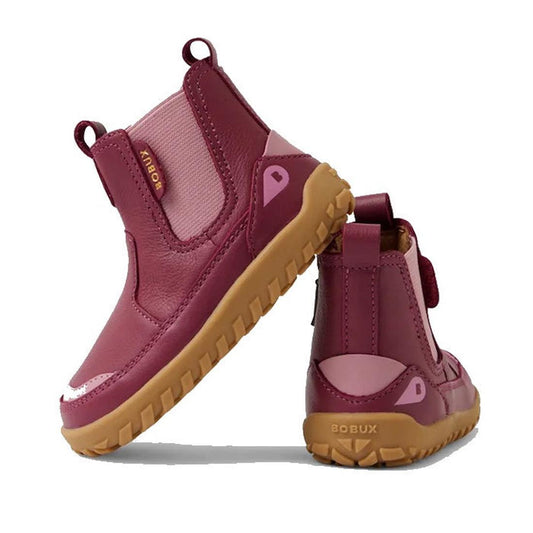Two Bobux SU Step Up Trail Leather Boots in Beaujolias Purple Alpha with tan rubber soles. One boot stands upright, the other is propped, highlighting the barefoot-shaped toe-box and "BOBUX" branding on the heel.