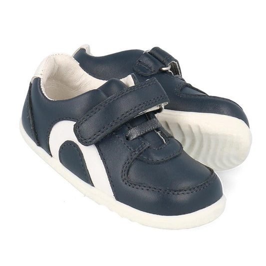 The Bobux Step Up SU Toddlers Leather Sneaker Comet Navy 734603 is a navy kids sneaker with white soles, side accents, hook-and-loop strap, elastic laces for easy fastening, and a flexible sole for comfort.