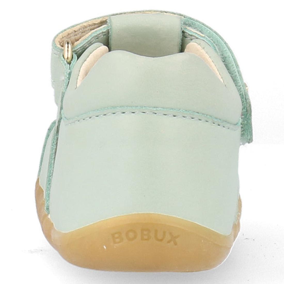 A close-up rear view of the Bobux Step Ups Compass Mist Aqua 734905 toddler girls sandal in light green leather with a tan rubber sole, featuring the BOBUX name embossed on the back—highlighting this stylish first walker., 9420075708594, 9420075708600, 94, 9420075708617, 9420075708624