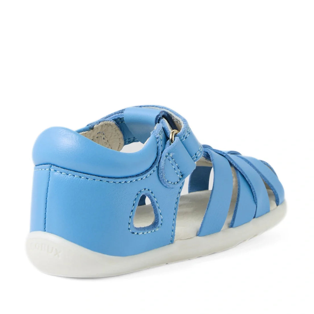 The Bobux Step Up SU Tropicana II Baltic Sea Blue Closed Toe Sandal is shown from a rear side angle. This toddler leather sandal features a closed heel, open sides, white sole, and a convenient hook-and-loop strap inspired by Bobux Tropicana sandals for e