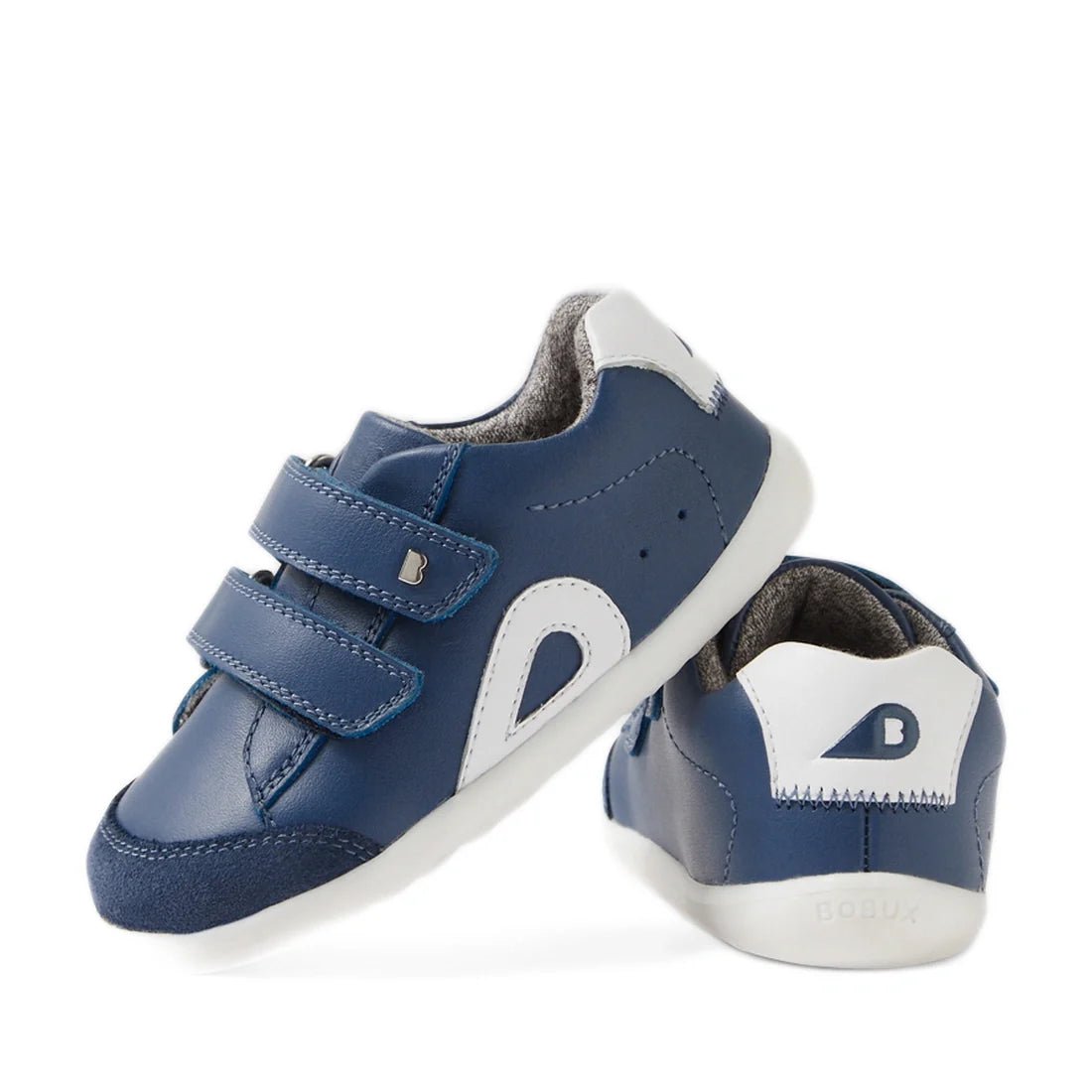A pair of Bobux SU Step Up Blaze Leather Toddlers Sneakers in Vintage Indigo, featuring blue and white quick-drying leather, soft soles ideal for first walkers, velcro straps, and a small B logo on the heel—one shoe displayed facing forward and the other 