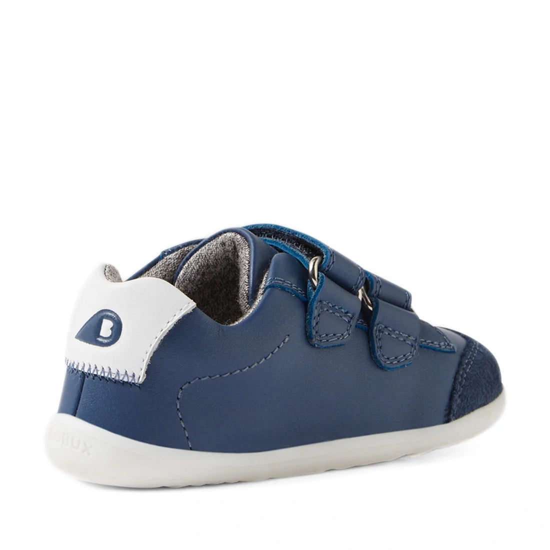 The Bobux SU Step Up Blaze Leather Toddlers Sneaker in Vintage Indigo is a blue leather first walker shoe for kids, featuring a white heel, gray inner lining, two hook-and-loop straps, and a white quick-drying rubber sole—shown at an angled back left view
