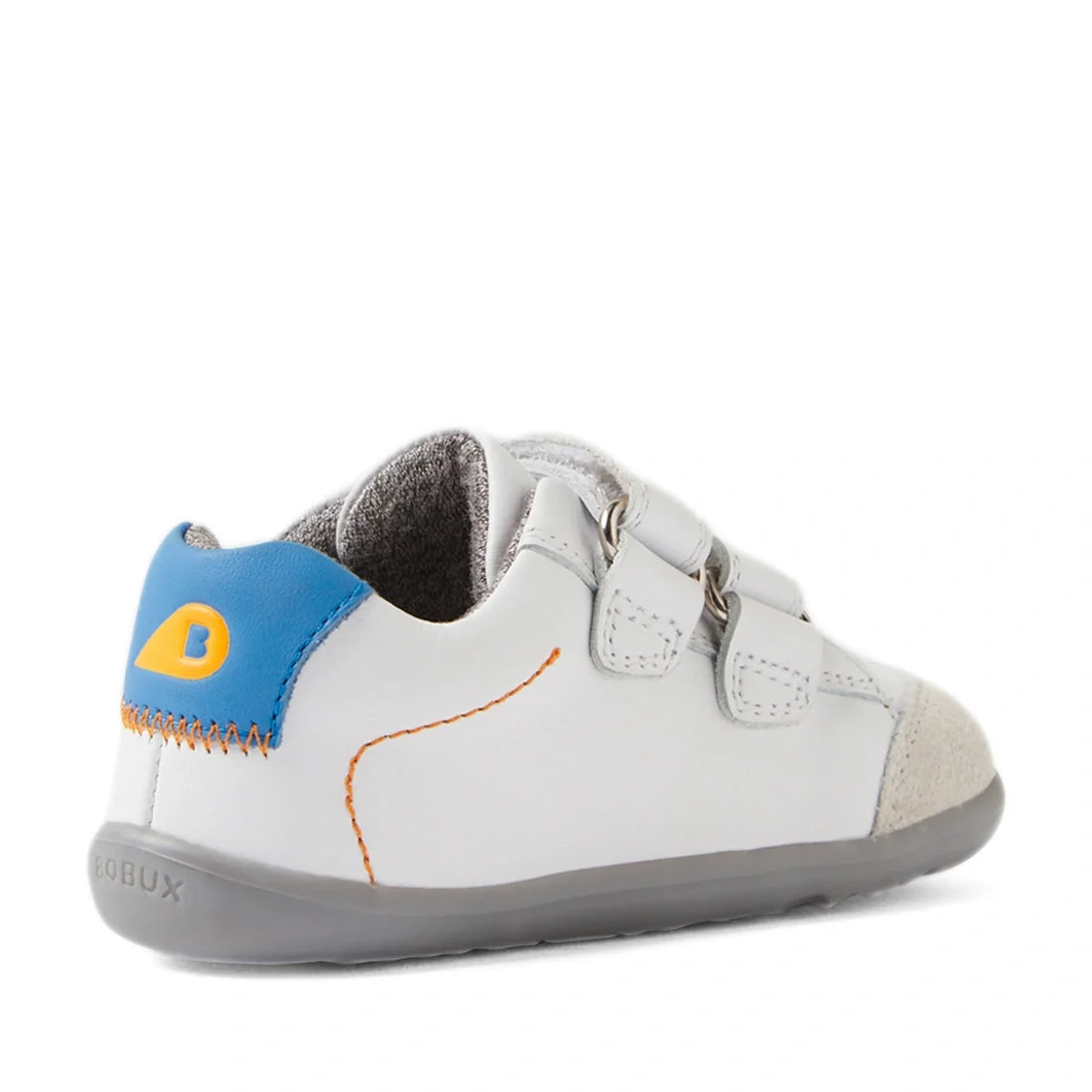 The Bobux SU Step Up Blaze Leather Toddlers Sneaker in White Orange features gray soles, blue and yellow heel accents, orange stitching, double Velcro straps, and suede toe detailing—angled to highlight both the side and back. These leather sneakers are a