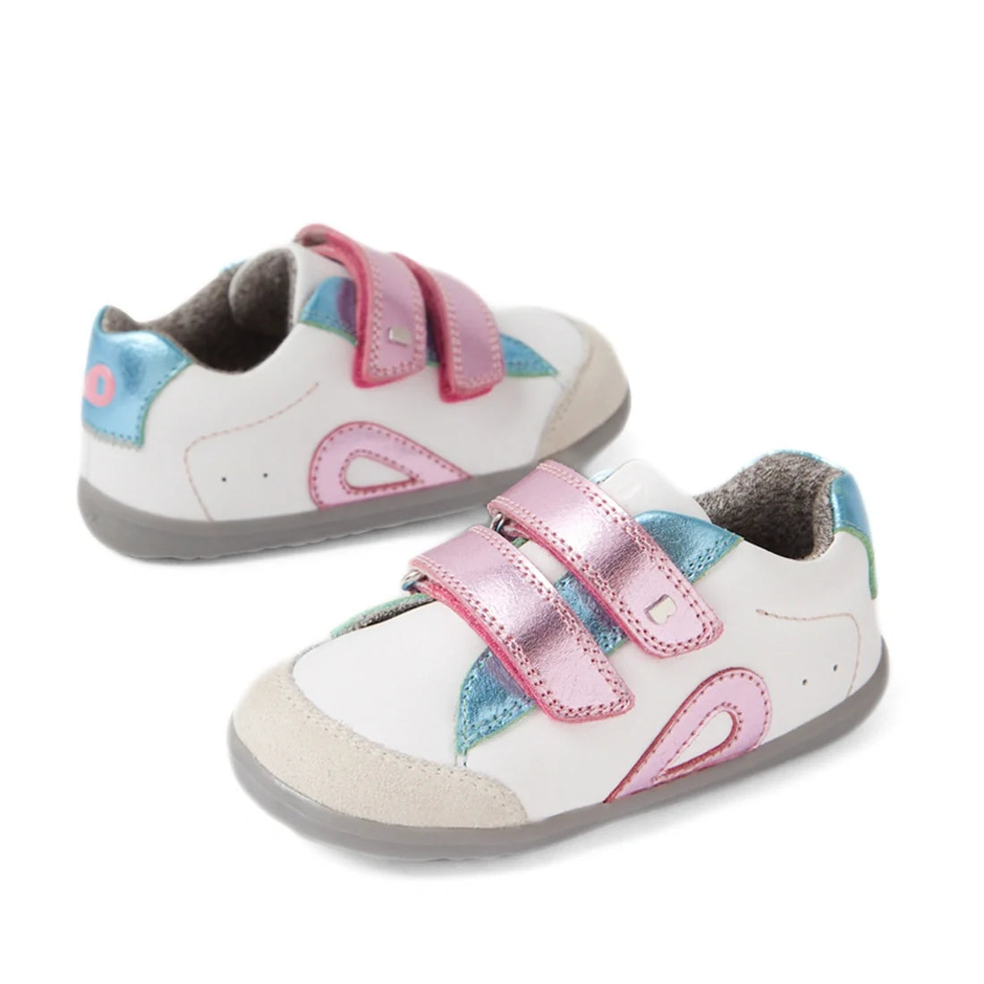 The Bobux SU Step Up Blaze Leather Toddlers Sneaker in White Pink features white leather with blue and pink accents, shiny pink velcro straps, and grey soles—making them the perfect first walking shoes for your little one.