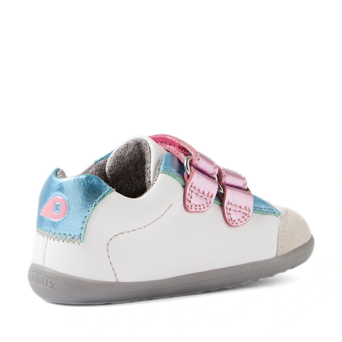 The Bobux SU Step Up Blaze Leather Toddlers Sneaker in White Pink features a gray sole, pink double straps, blue metallic and pink accents on the heel and tongue, and a beige toe cap. Shown at an angle from the back left side, these adorable kids’ leather