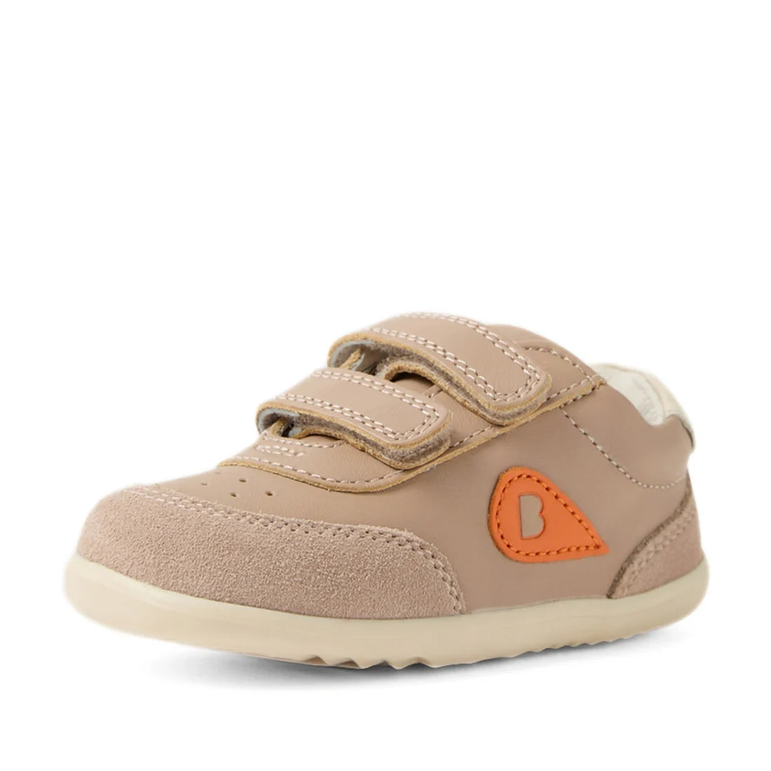 The Bobux Step Up SU Champ Sneaker First Walker in Warm Taupe is a beige leather sneaker for toddlers, featuring two hook-and-loop straps, a light sole, and an orange “B” patch on the side. Designed for young children, these shoes offer a rounded toe for 