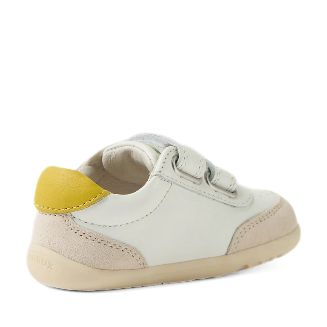 The Bobux Step Up SU Champ Sneaker First Walker in White Green is a small, white kids’ leather sneaker with green accents, a beige sole, and easy hook and loop straps, featuring a green patch on the heel—perfect for first walkers. Shown from a rear side a
