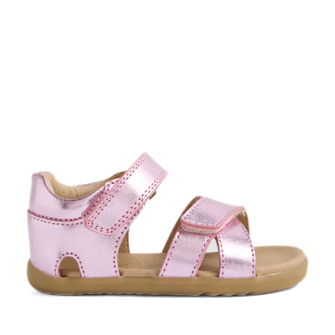 The Bobux Step Up Flora First Walker Sandal in Pink Lemonade Metallic is a children’s metallic pink leather sandal, featuring a closed heel, two adjustable Velcro straps, an open toe, and a tan rubber sole. It is displayed in a left side profile on a whit