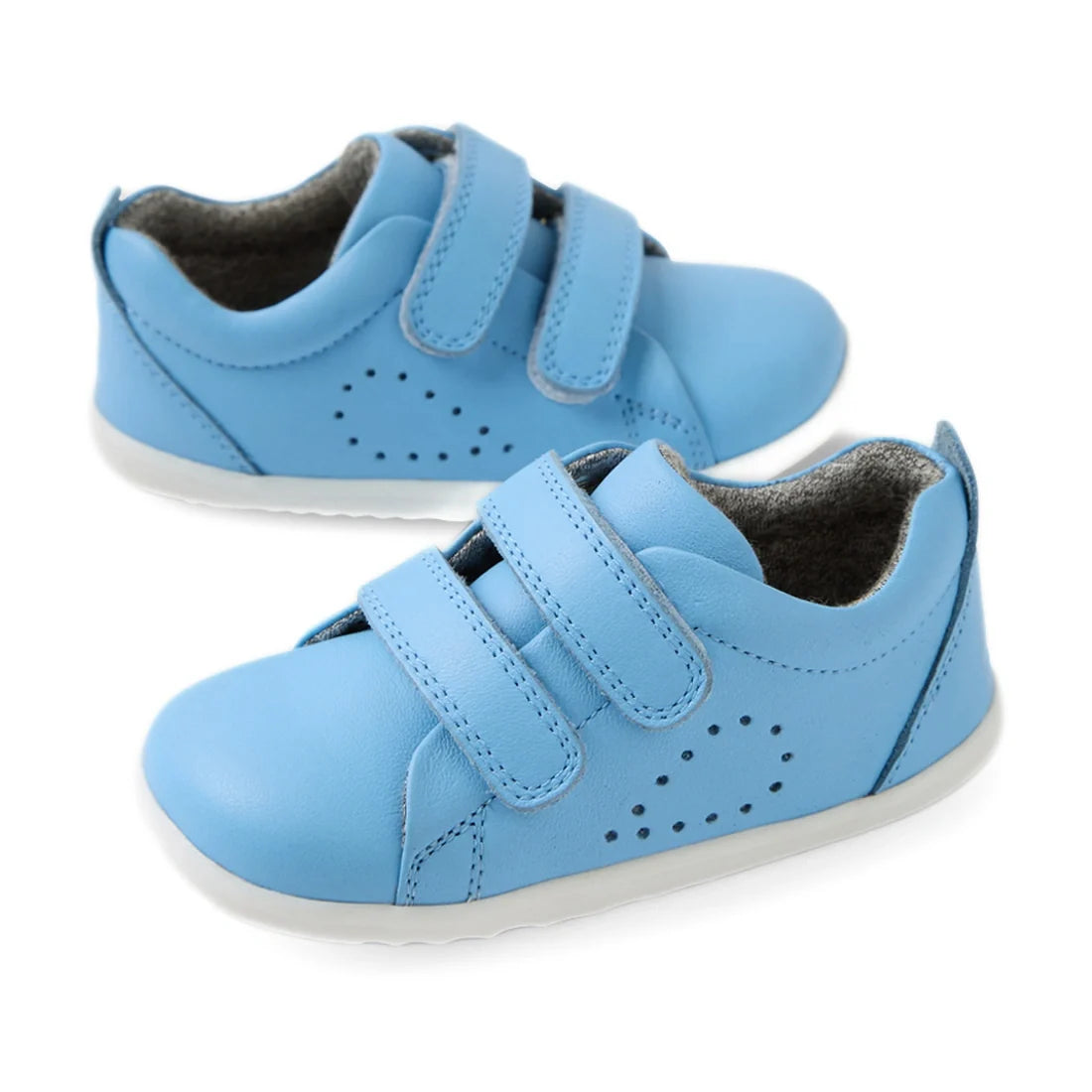 A pair of Bobux Step Up Grass Court Trainer Baltic Sea Blue kids’ leather sneakers with white soles and two Velcro straps, perfect as first walkers, displayed on a white background.