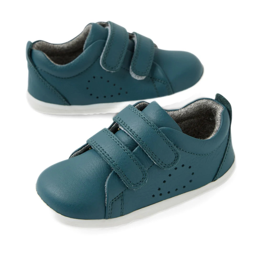 A pair of Bobux Step Up Grass Court Trainer toddler shoes in Mediterranean Green with white soles and Velcro straps, positioned on a white background.