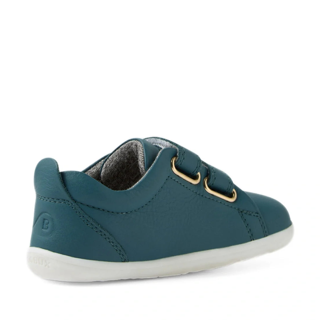 A Mediterranean green leather kids’ sneaker, the Bobux Step Up Grass Court Trainer, features two hook-and-loop straps, stitched detailing, and a white rubber sole. This first walker sneaker is shown from a rear side angle., 9420074806246, 9420074806253, 9